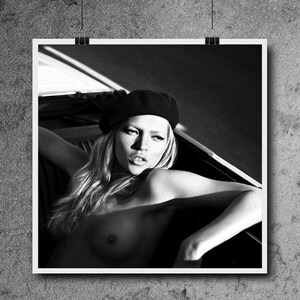 Peut inclure: Une photo en noir et blanc d'une femme portant un b&eacute;ret noir et regardant vers le c&ocirc;t&eacute;. Elle est assise dans une voiture et ses &eacute;paules et sa poitrine sont d&eacute;couvertes.