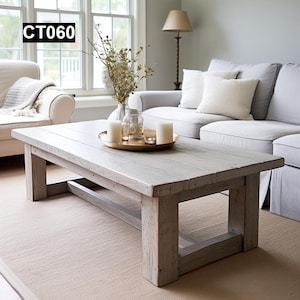 May include: A light grey, rectangular wooden coffee table with a distressed finish. The table has a lower shelf and is in a living room setting. The text "CT060" is in the upper left corner. A gold tray with candles and a vase of flowers sits on top.