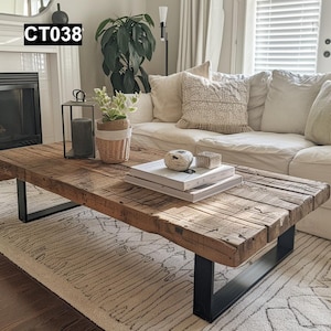 May include: A rectangular, rustic coffee table with a distressed wood top and black metal legs. The table is in a living room setting, with a white sofa, rug, and decorative items like books and a candle lantern. The text "CT038" is in the top left corner.