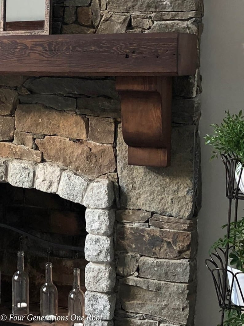 May include: A rustic stone fireplace with a wooden mantel and a decorative wooden corbel. The fireplace is surrounded by a variety of stonework, including granite and slate.