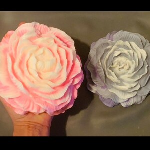 May include: Two handmade soap flowers, one in pink and white and the other in purple and white.
