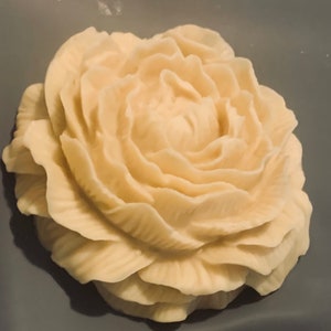 May include: A white, handmade soap shaped like a rose. The soap has a detailed, layered design.