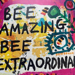 Könnte beinhalten: Abstraktes Kunstwerk mit den Worten "BEE AMAZING BEE EXTRAORDINARY" in Schwarz. Der Hintergrund ist eine Mischung aus Weiß, Gelb, Rosa und Türkis, mit bunten Pinselstrichen und Formen.