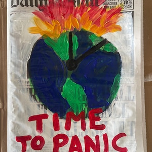 May include: A painting on a Daily Mail newspaper page featuring a blue and green globe with black clock hands. Above the globe are painted red, orange, and yellow flames. Below the globe, the text TIME TO PANIC is painted in bold red letters.