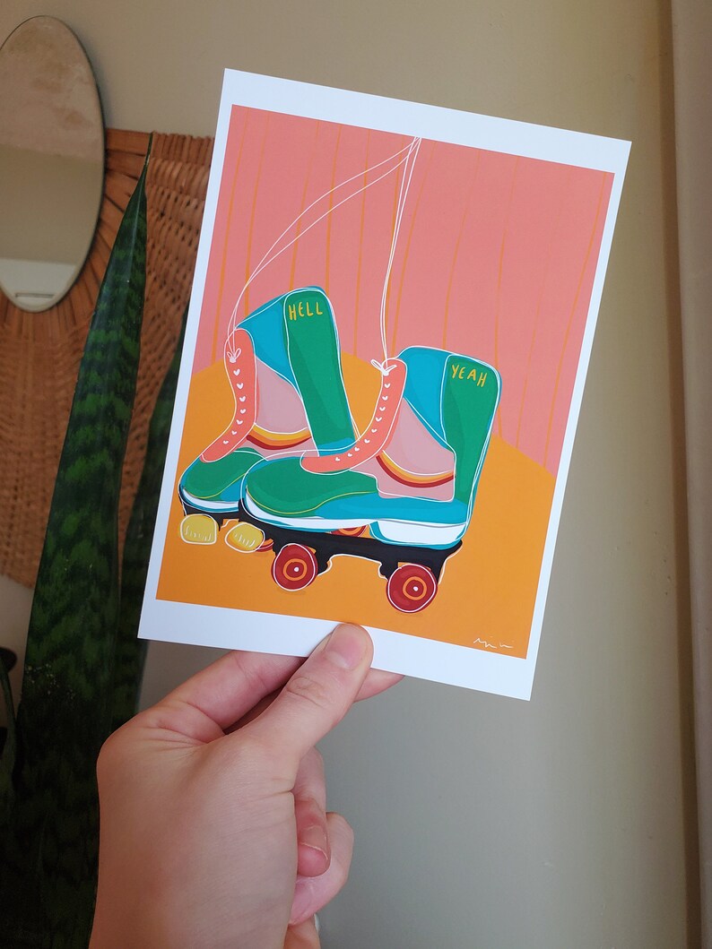 Puede incluir: Un par de patines de ruedas verdes y azules con ruedas rosas. Los patines tienen las palabras "Hell Yeah" escritas en ellos.