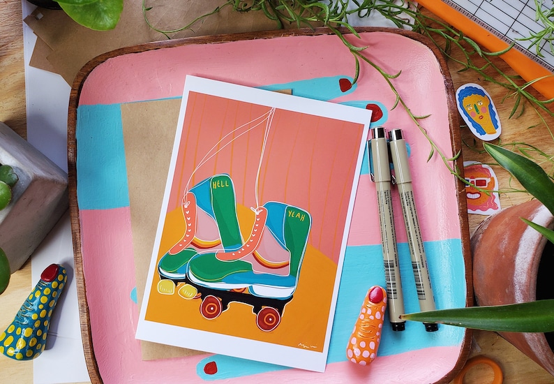 Puede incluir: Una tarjeta de felicitaci&oacute;n con una ilustraci&oacute;n colorida de un par de patines. Los patines son verdes, azules y rosas con ruedas amarillas. El texto "Hell Yeah" est&aacute; escrito en los patines.