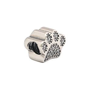 May include: Silver charm in the shape of a paw print with clear sparkling stones. The charm is designed to be used on a bracelet or necklace.