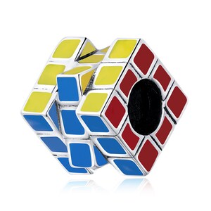 Puede incluir: Un charm de plata con forma de cubo de Rubik con esmalte rojo, amarillo y azul. El charm está diseñado para encajar en una pulsera o collar.