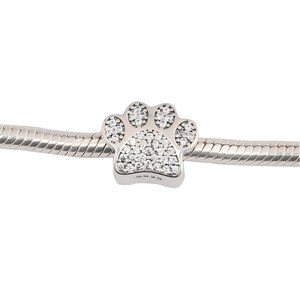 May include: A silver charm in the shape of a paw print, encrusted with clear cubic zirconia stones.