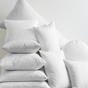 May include: A stack of white pillows of various sizes and shapes, arranged in a pyramid formation.