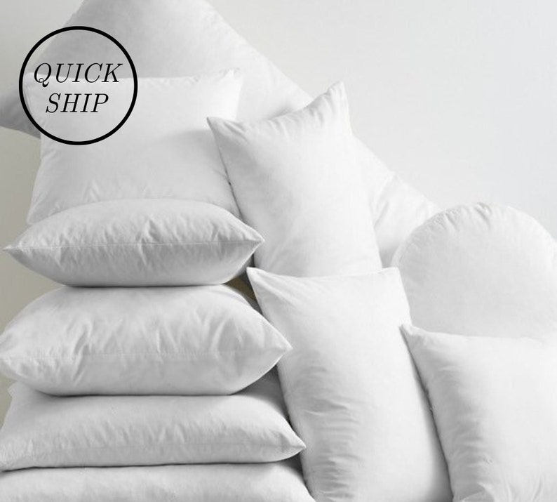 May include: A stack of white pillows of various sizes and shapes. The pillows are arranged in a pyramid shape. The top pillow has the words "QUICK SHIP" written on it.