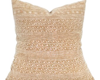 May include: A square throw pillow featuring a tan fabric base with a repeating white dotted pattern arranged in horizontal bands. The design consists of small, light-colored marks that create a textured appearance across the entire surface.