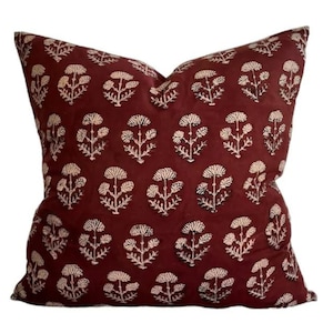 May include: A burgundy throw pillow with a white floral pattern. The pillow is made of a soft, cotton fabric and is perfect for adding a touch of elegance to any room.