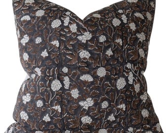 May include: A square decorative pillow with a floral pattern. The pillow features a dark gray background with a repeating design of white flowers and brown leaves. The pillow is a soft, comfortable home decor item.