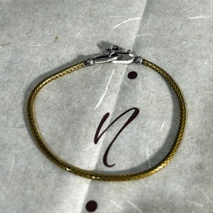 May include: A gold braided chain bracelet with a silver clasp.