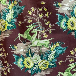 May include: A brown fabric with a repeating pattern of green and yellow stylised flowers, leaves, and deer. The deer are running through a forest scene.