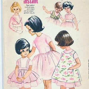 May include: A vintage sewing pattern envelope featuring illustrations of children wearing various dresses. The text reads: instant, Paper pattern is all one piece, pin to fabric and cut complete garment instantly. The dresses are pink, white, and floral.