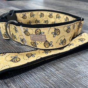 May include: A yellow and black dog collar with a bee pattern and the text "Marielme Zoomies".