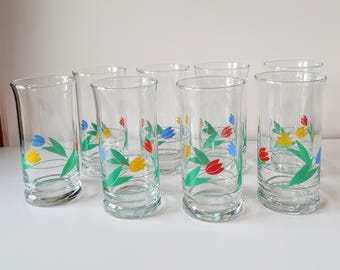 May include: Set of eight clear glass drinking glasses with a floral design. The glasses feature a repeating pattern of stylized tulips in shades of blue, yellow, red, and green.