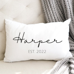May include: White throw pillow with black cursive text that reads "Harper EST. 2022".