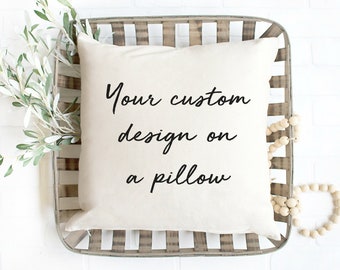 May include: A white pillow with the text "Your custom design on a pillow" printed in black on it. The pillow is sitting in a wooden tray with a white background.