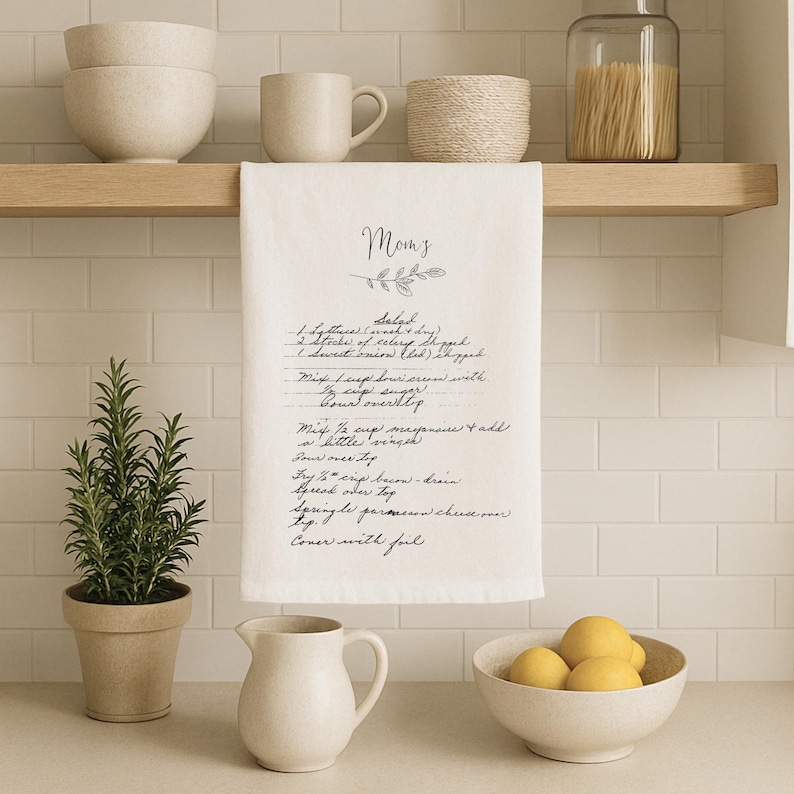 May include: A white kitchen towel with a handwritten recipe for "Mom's Salad" printed on it. The recipe includes ingredients like celery, onion, and mayonnaise.