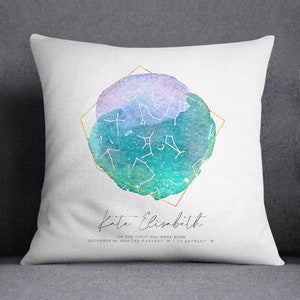 May include: A white throw pillow with a watercolor design of a constellation in a gold frame. The text "Kate Elisabeth" and "On the night you were born" is printed below the design, along with the date and coordinates.