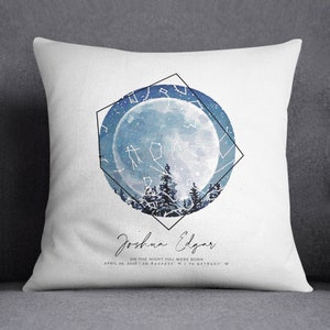 May include: A white throw pillow with a blue watercolor moon and stars design. The pillow features a geometric frame and the text "Joshua Edgar" with the date "April 25, 2016" and coordinates "39.8432431° N 74.9778507° W".