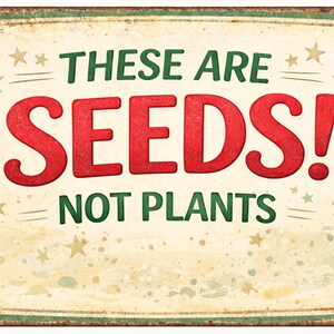 May include: A vintage-style metal sign with the text "THESE ARE SEEDS! NOT PLANTS" in red and green. The sign has a distressed, aged appearance with star accents and a cream-colored background.