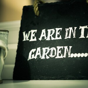 May include: Black chalkboard sign with white text that reads "We are in the garden..." with a small white watering can icon.