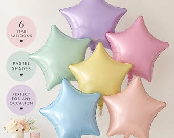 May include: A set of six star-shaped foil balloons in pastel shades of lavender, mint green, pale yellow, light pink, baby blue, and peach. The balloons are arranged in a cluster, each featuring a smooth, metallic finish and a five-pointed star design.