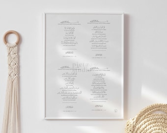 May include: A white framed print featuring black Arabic calligraphy text. The text is divided into four sections, each with a title. The print is displayed on a white wall with a wooden table below it. Two decorative items, a white vase and a round woven basket, are placed on the table.