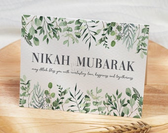 May include: A white card with green foliage border and the text "NIKAH MUBARAK" in black. The text below reads "may Allah bless you with everlasting love, happiness and togetherness".