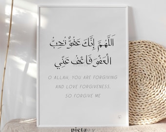 May include: A framed white print featuring Arabic calligraphy and an English translation. The text says "O Allah, You are Forgiving and Love Forgiveness, So Forgive Me." The print is displayed on a beige surface.