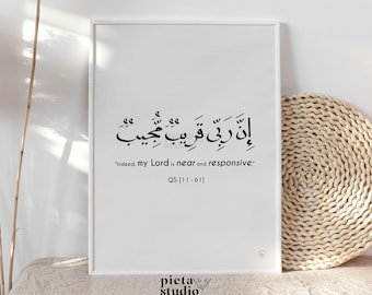 May include: A white framed print with black Arabic calligraphy and the English translation "Indeed, my Lord is near and responsive." The text also includes the Quran reference "QS. [11:61]".