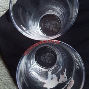 Puede incluir: Dos vasos de pinta de pl&aacute;stico transparente con gr&aacute;ficos en blanco y negro. El vaso superior tiene el texto "WITH FLAVOUR CHARGED" en rojo. El vaso inferior tiene el texto "PREMIUM BULLEN BEECH" y "WATT" en blanco.
