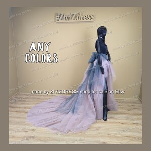 May include: A black mannequin showcases a layered tulle skirt with a long train. The skirt fades from pink to grey-blue. The text "ANY COLORS" is visible, along with the shop's name.