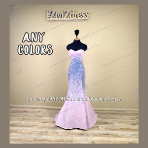 May include: A strapless, floor-length gown on a mannequin. The dress transitions from a light pink at the bottom to a blue-grey in the middle, with a sweetheart neckline. The words "ANY COLORS" are displayed in large, bold letters.