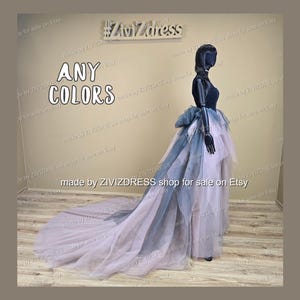 May include: A layered tulle skirt in shades of lavender, grey, and navy blue, with a long train. The skirt is displayed on a black mannequin. The text "ANY COLORS" is visible.
