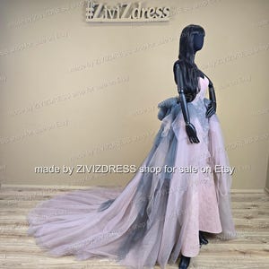 May include: A formal gown on a mannequin. The dress features a pink bodice, a layered skirt with gray and pink tulle, and a long train. The mannequin is black, and the background is a neutral beige. The text "#Ziv7dress" is visible.
