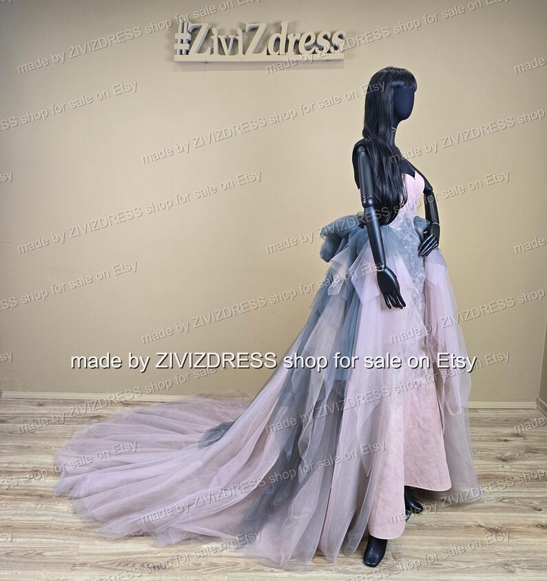 May include: A formal gown on a mannequin. The dress features a pink bodice, a layered skirt with gray and pink tulle, and a long train. The mannequin is black, and the background is a neutral beige. The text "#Ziv7dress" is visible.