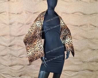 Könnte beinhalten: Ein schwarzes Kleid mit einem Leopardenmuster-Schal. Der Schal ist aus weichem, flauschigem Material und hat eine braune und schwarze Farbgebung.
