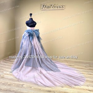 May include: A formal gown on a mannequin. The dress features a light pink and blue layered skirt with a long train. A large blue bow accents the back. The bodice is white. The shop name "Zivizdress" is visible.