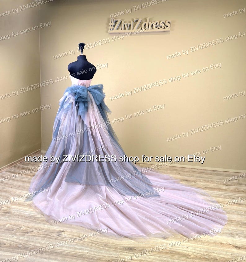 May include: A formal gown on a mannequin. The dress features a light pink and blue layered skirt with a long train. A large blue bow accents the back. The bodice is white. The shop name "Zivizdress" is visible.