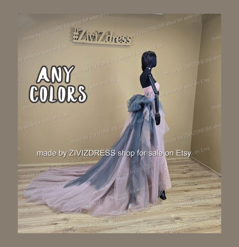May include: A strapless, floor-length gown on a mannequin. The dress features a pink bodice, a large blue-gray bow, and a flowing train that transitions from pink to blue-gray. The text "ANY COLORS" is visible.