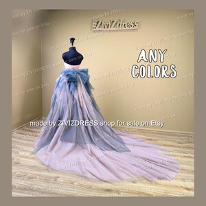 May include: A formal gown with a layered skirt and a long train. The bodice is a light pink, with a blue bow. The skirt is a combination of blue and pink tulle. The text "ANY COLORS" is visible.