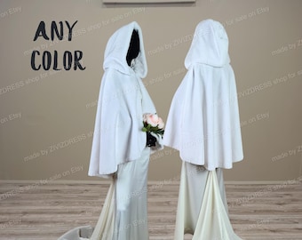 Puede incluir: Dos capas de novia blancas con capucha y largas colas. Las capas están hechas de una tela suave y esponjosa y tienen un diseño simple y elegante. El texto "ANY COLOR" es visible en la imagen.