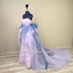 May include: A strapless, floor-length gown on a mannequin. The dress features a pale pink bodice and a flowing skirt with layers of blue and lavender tulle. The train extends behind the mannequin. The text "made by ZIVIZDRESS shop for sale on Etsy" is visible.