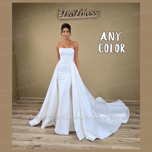 May include: A strapless white wedding gown with a flowing train. The dress features a fitted bodice and a long, elegant skirt. The text "ANY COLOR" is visible in the image.
