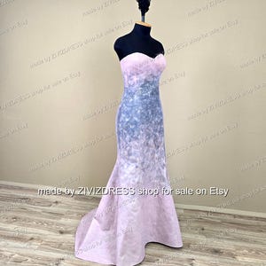Puede incluir: Vestido largo sin tirantes sobre un maniqu&iacute; negro. El vestido hace la transici&oacute;n de un rosa claro en la parte superior a un patr&oacute;n geom&eacute;trico azul gris&aacute;ceo en el medio, terminando con un dobladillo de cola de pez rosa. El texto en la imagen dice "made by ZIVIZDRESS shop for sale on Etsy."